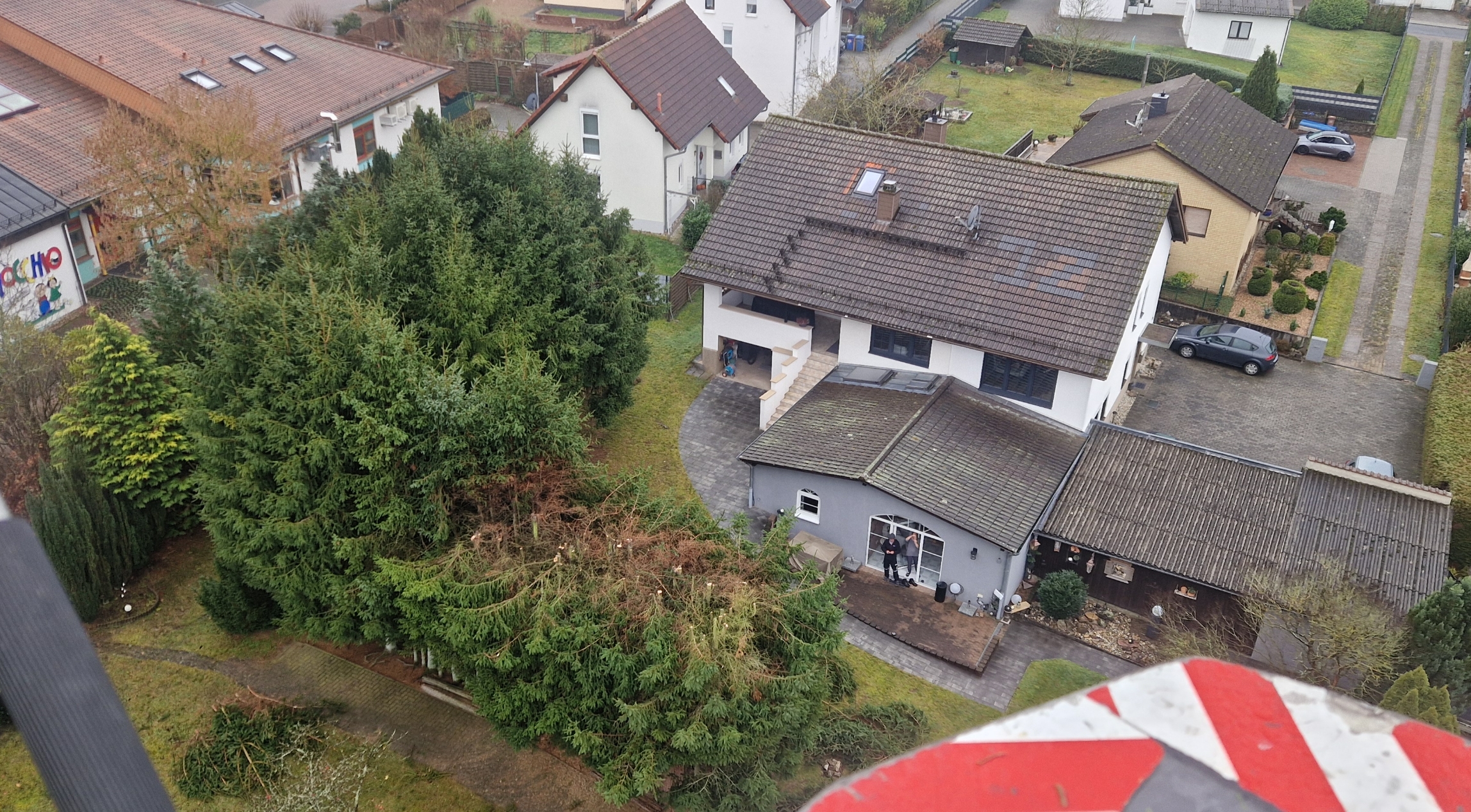 Vogelperspektive eines Hauses mit einem großen Garten, umgeben von grünen Bäumen und Nachbarhäusern in einer Wohnsiedlung.